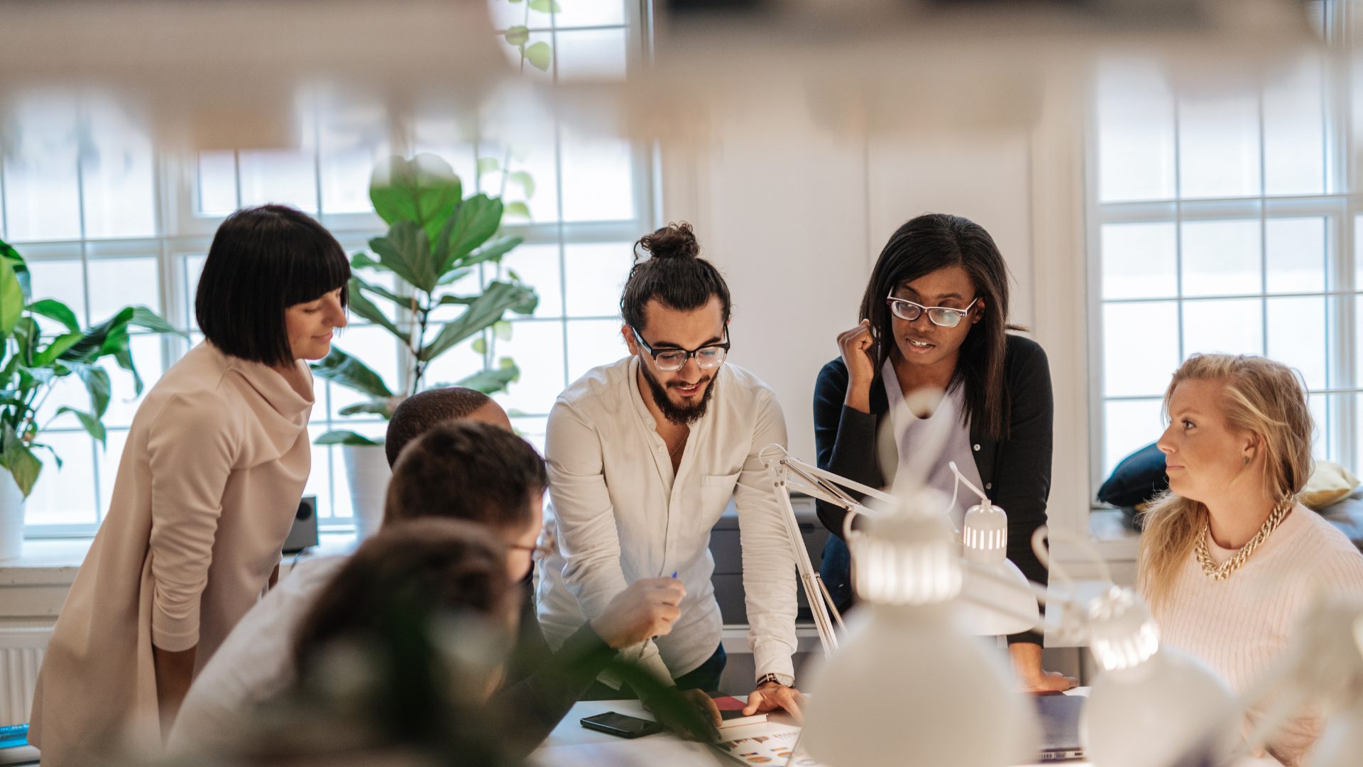 Local SEO, Five diverse professionals at a local web design firm brainstorming and engaging over documents in a modern, well-lit office environment. Team members eagerly update their contact details for optimal collaboration. Web Design, East Texas